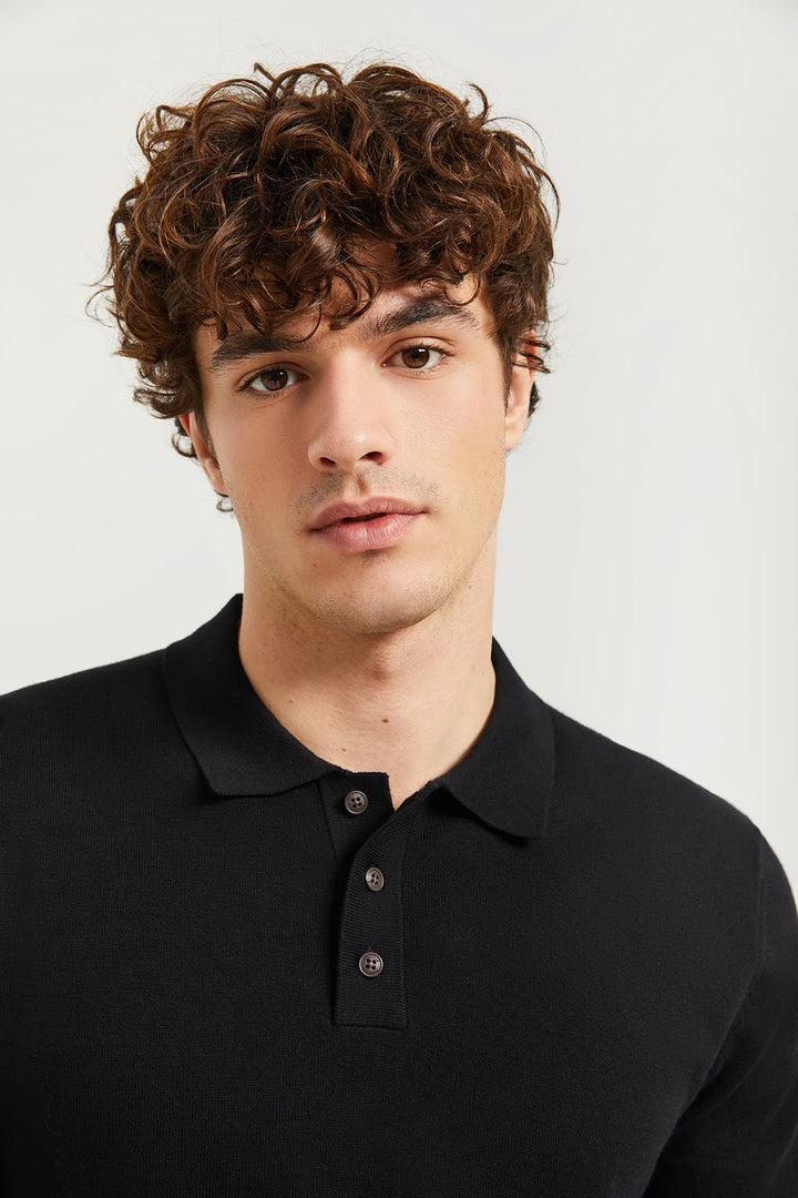 Polo de punto negro con detalle en el bajo